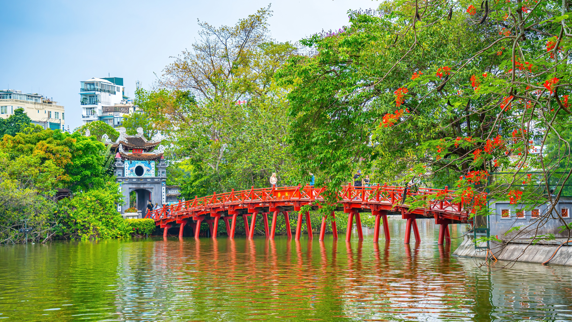 Le pont The Huc menant au temple Ngoc Son sous des arbres verdoyants