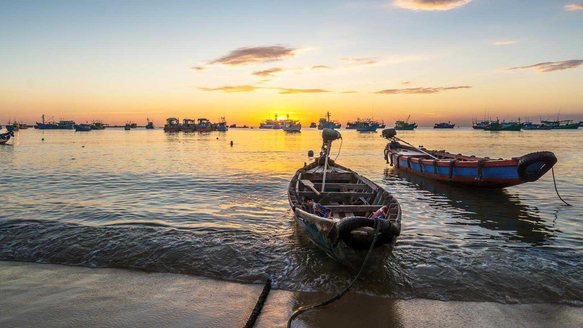 Barques de pêche traditionnelles sur le rivage de Phu Quoc sous un ciel doré de fin de journée