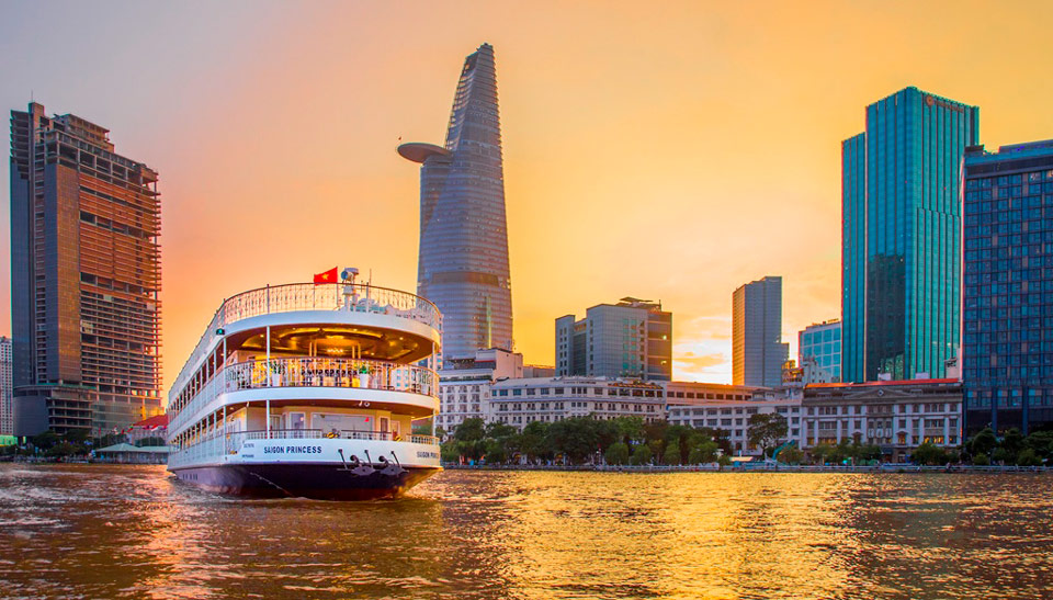 Bateau de croisière naviguant sur la rivière Saigon devant les bâtiments modernes du centre-ville