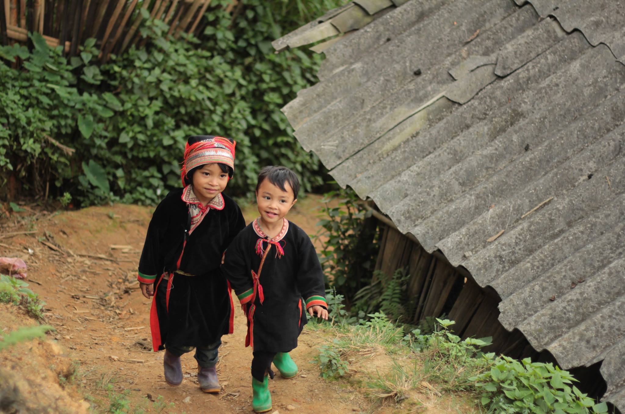 Deux enfants en costume traditionnel marchant près d'une maison rurale